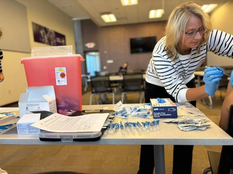 Pharmacy staff member preparing a vaccination at a clinic table